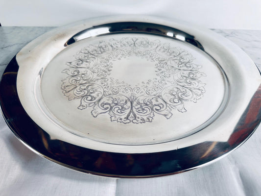 Silver tray with intricate designs on a white marble surface