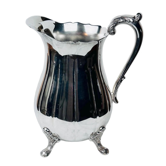 Silver pitcher on a marble surface with a white background