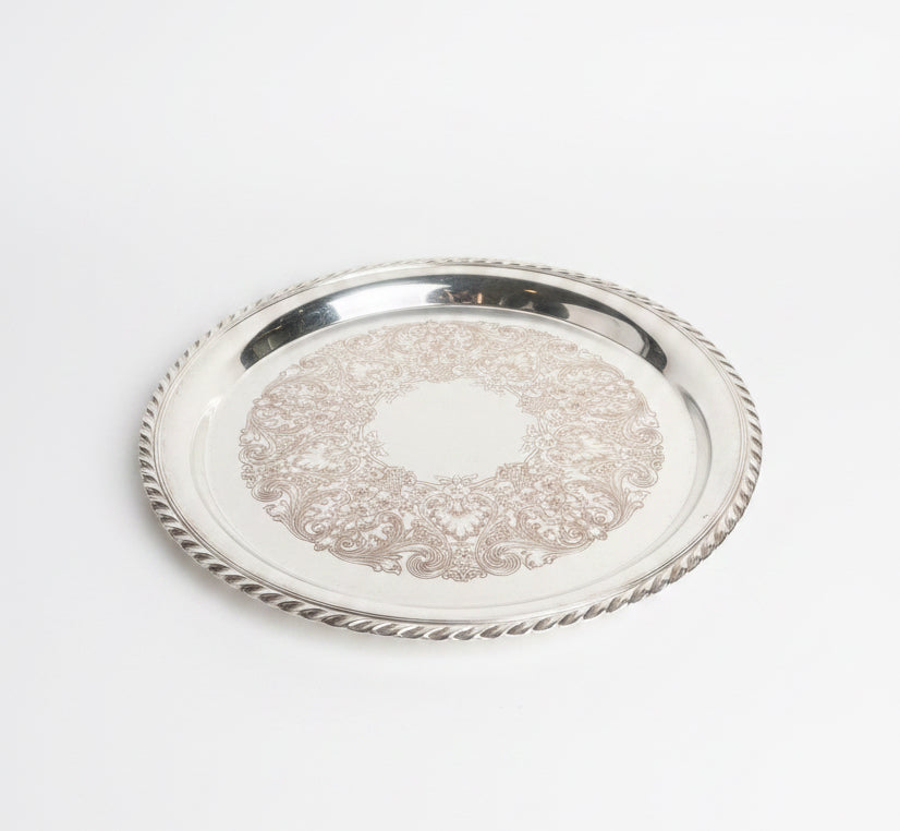 Silver tray with intricate designs on a marble surface