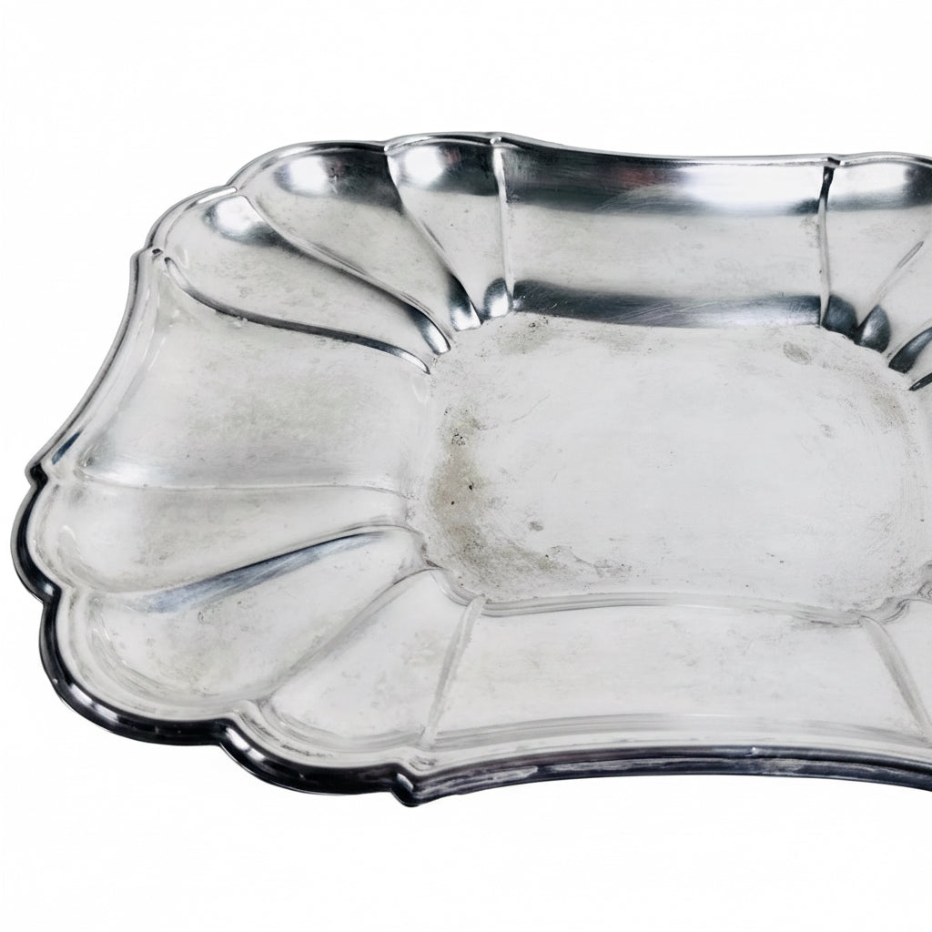 Silver shell-shaped dish on a marble surface with a light gray background