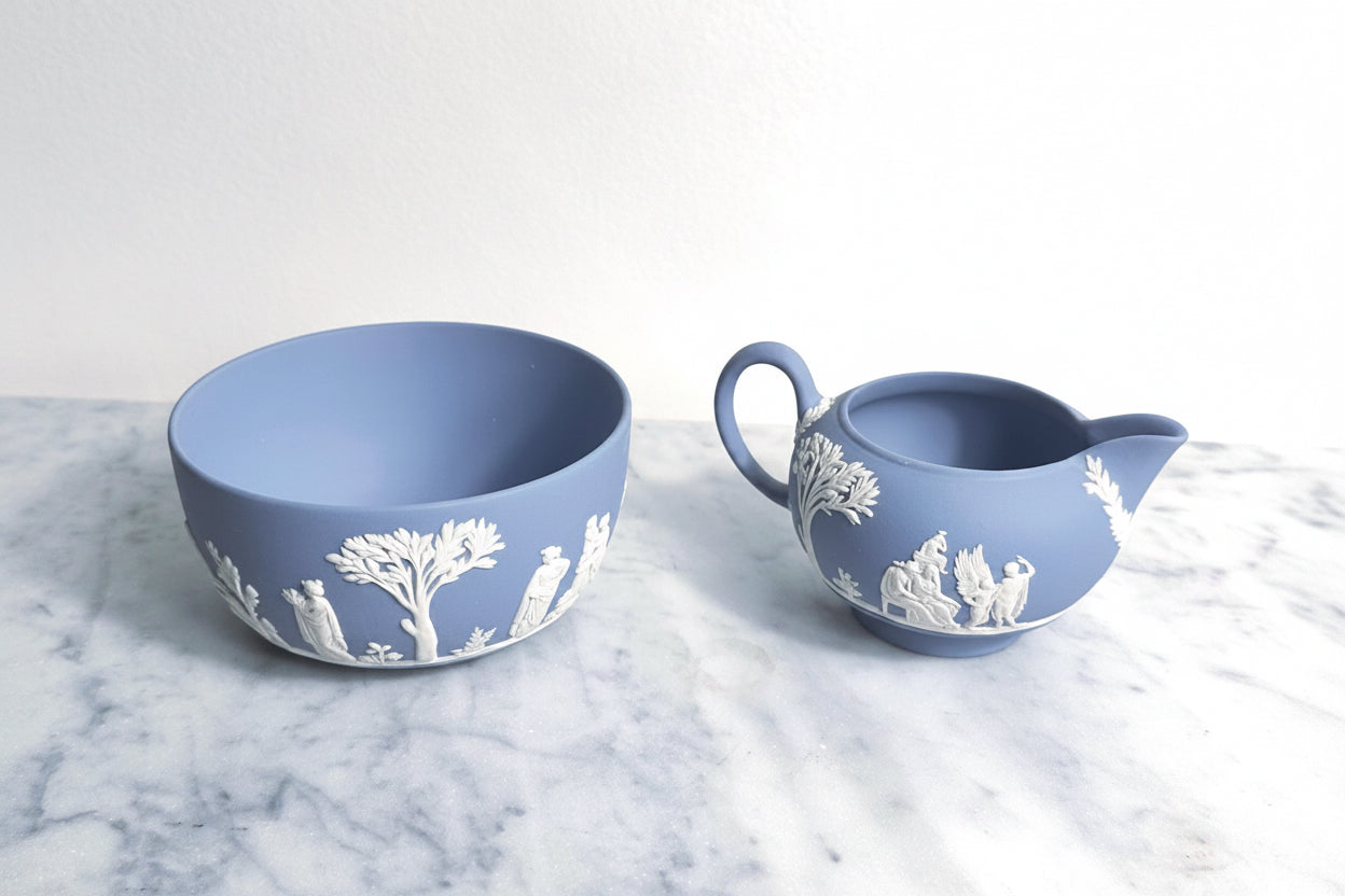 Blue ceramic bowl and pitcher with white relief patterns on a marble surface