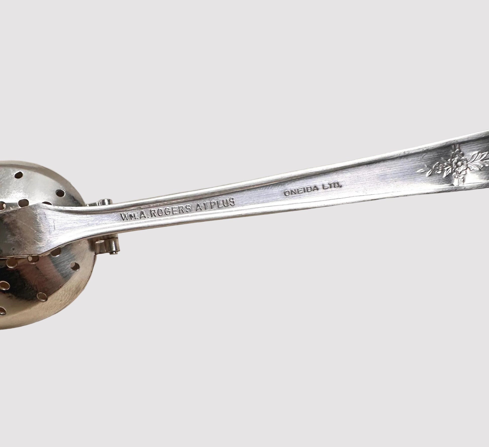 Silver ladle with decorative handle on a beige background