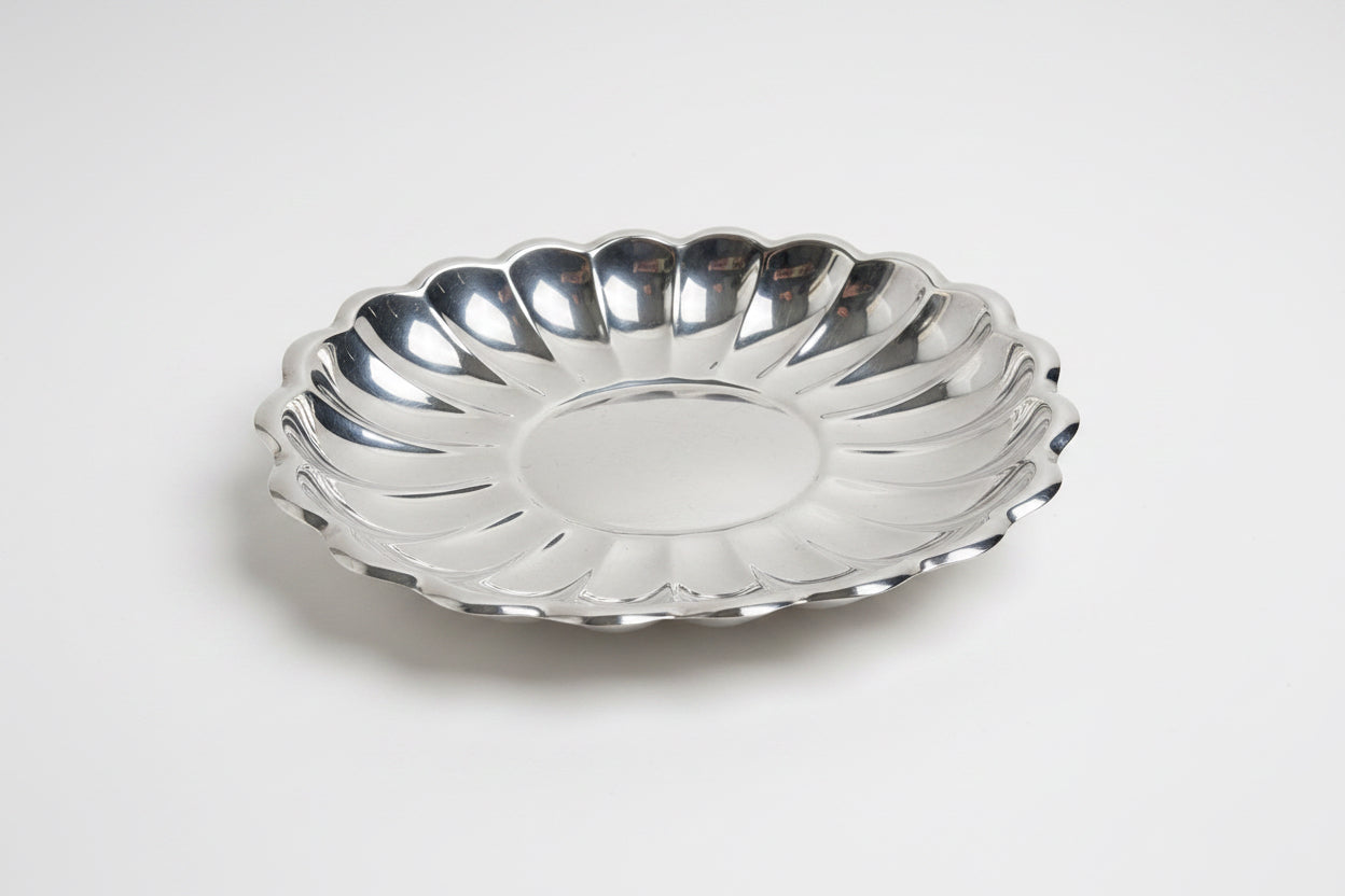 Silver decorative object with intricate patterns on a neutral background