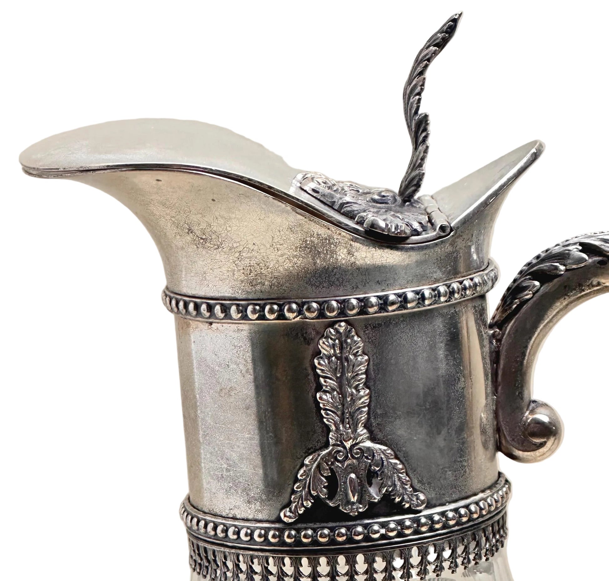 Silver pitcher with decorative elements on a beige background