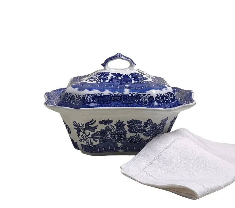 Blue and white patterned tureen with a white napkin on a beige surface
