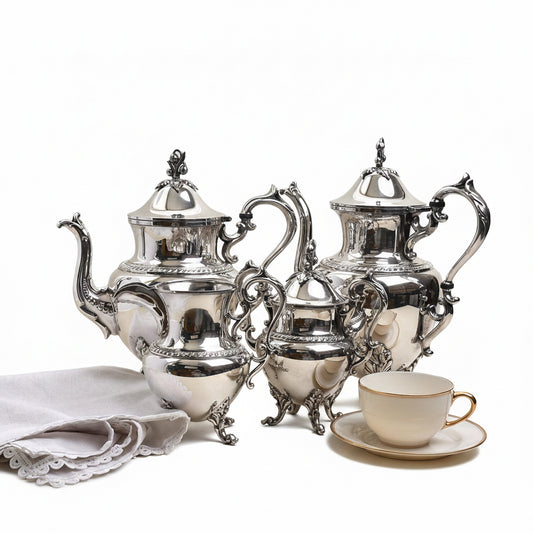 Silver tea set with teapot, coffee pot, and cup on a light background