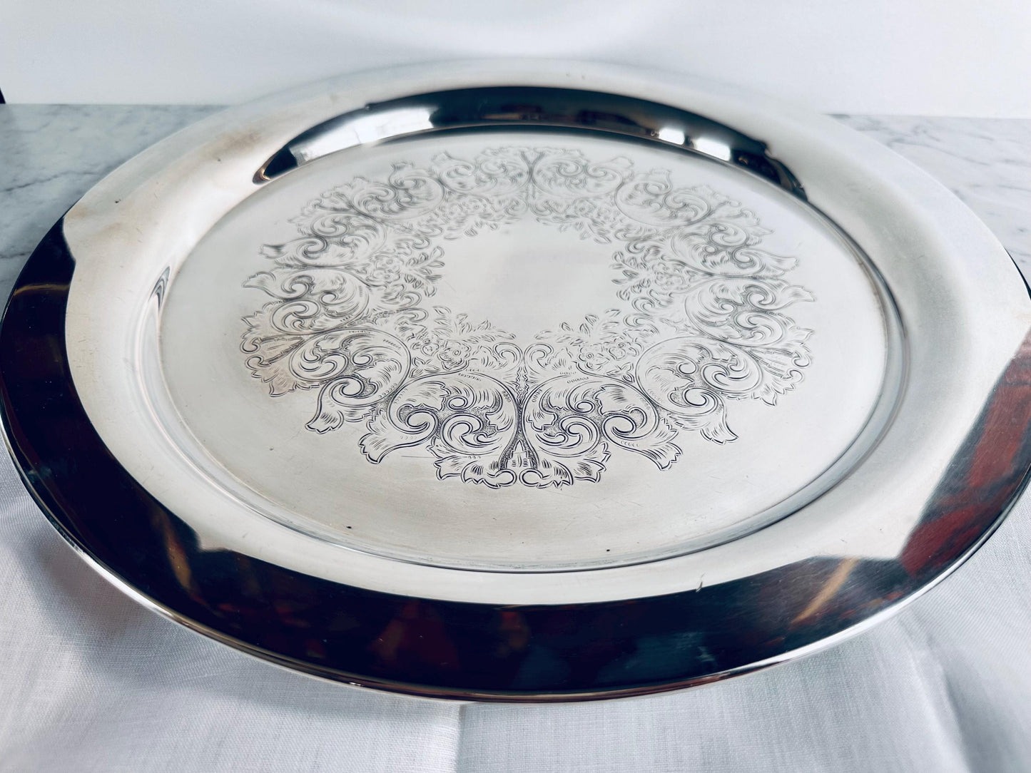 Silver tray with intricate designs on a white marble surface