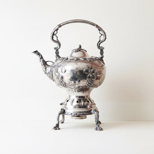 Silver teapot on a white cloth with a plain background