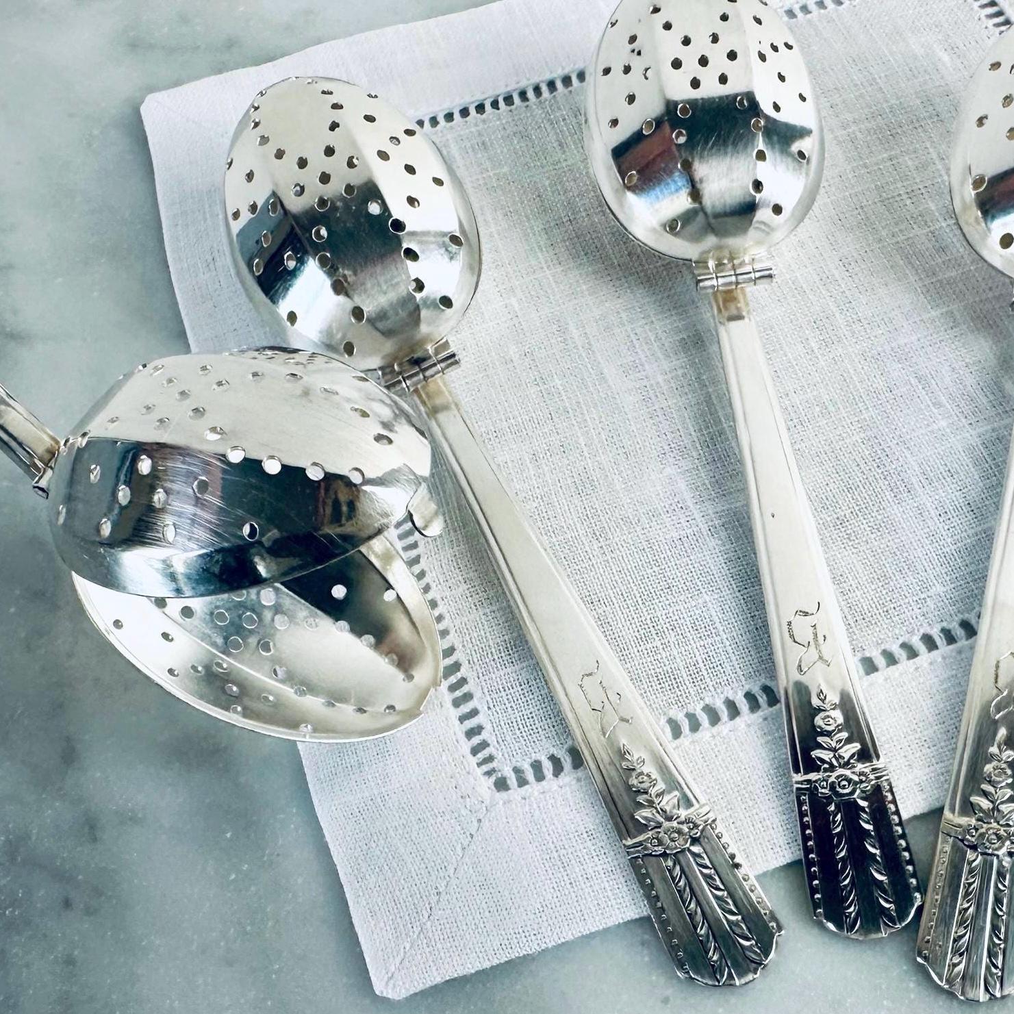 Silver tea infusers on a textured surface