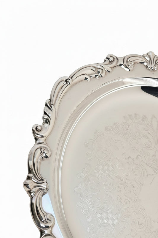 Silver tray with intricate designs on a beige background