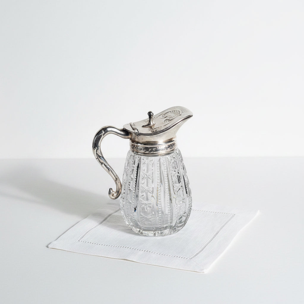 Clear glass cruet with silver top on a marble surface