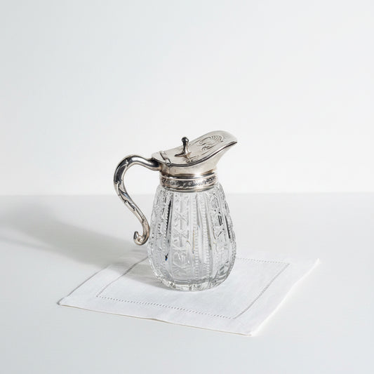 Clear glass cruet with silver top on a marble surface