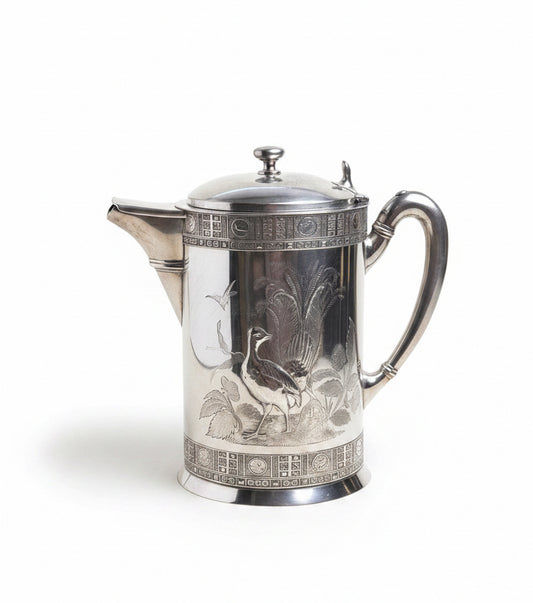 Silver teapot with detailed design on a white surface